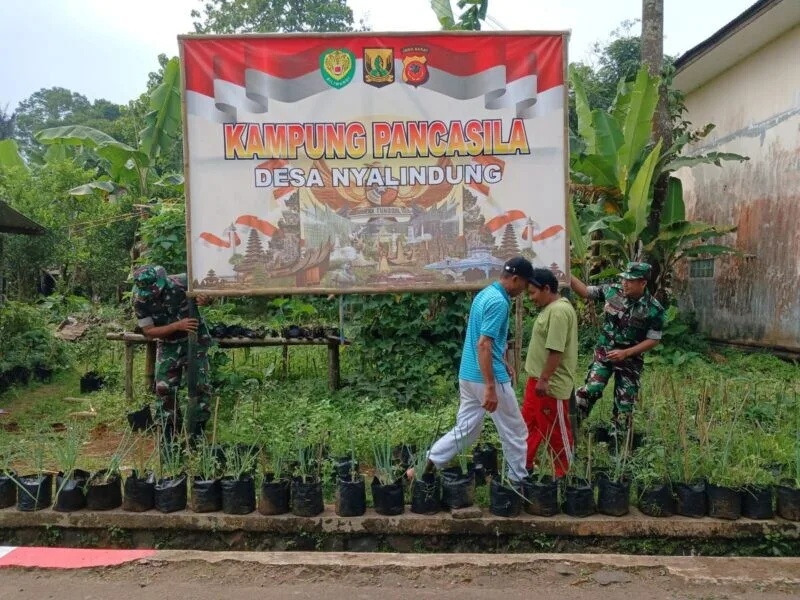 Babinsa Koramil 2208/Nyalindung Laksanakan Bakti Pemasangan Banner Kampung Pancasila