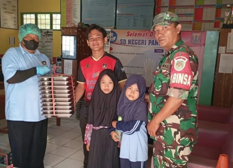 Babinsa Koramil 2212/Tegalbuleud Dampingi Kegiatan Makan Bergizi Gratis Bagi Anak Sekolah Di Desa Sumberjaya
